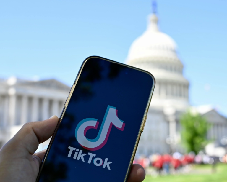 A phone displaying the TikTok icon in front of the U.S. Capitol building