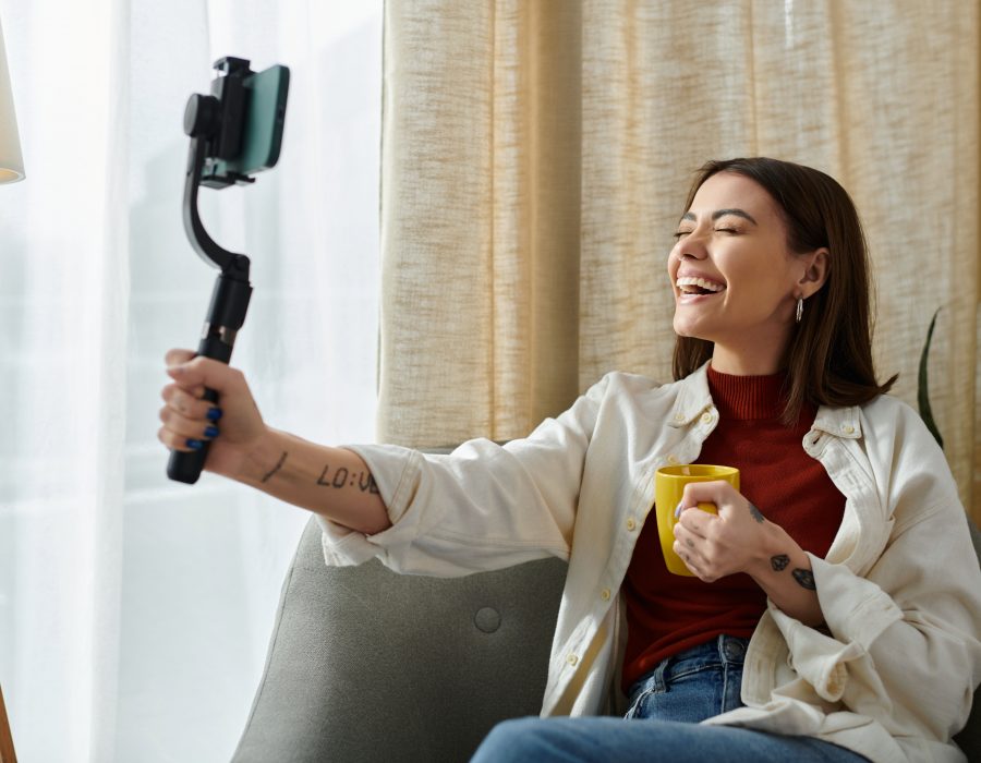 Cheerful Mavely creator with selfie stick and tattoos.